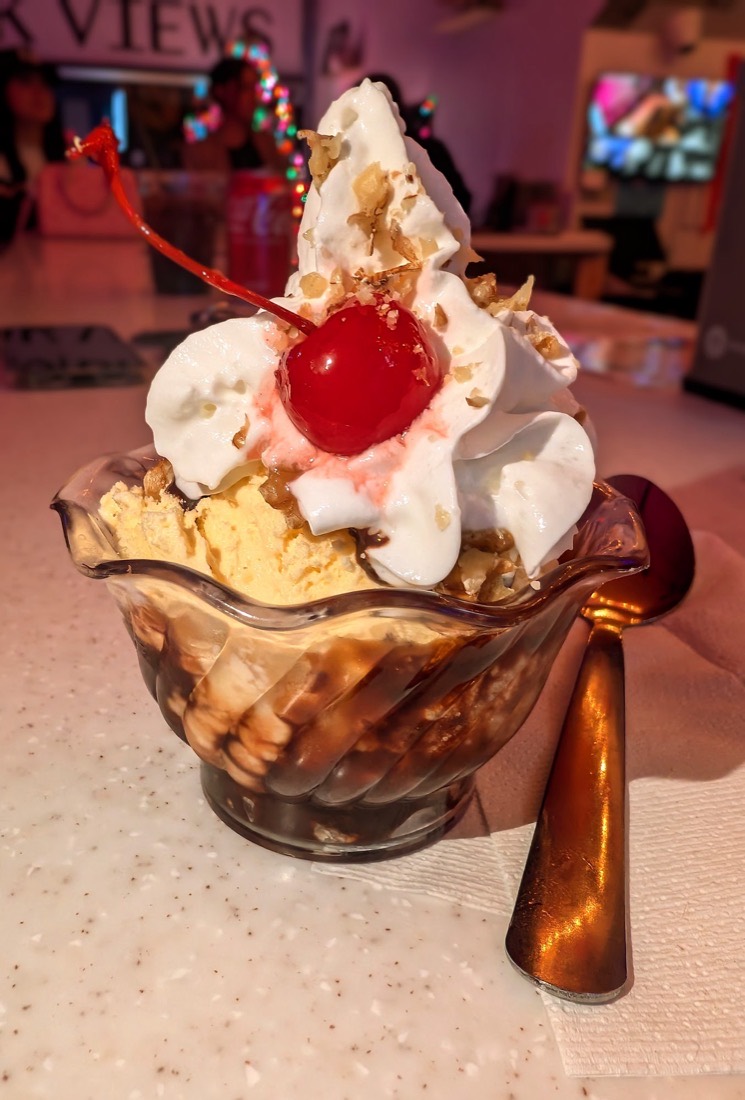 A vanilla sundae with chocolate syrup, whipped topping, walnuts and a cherry on top